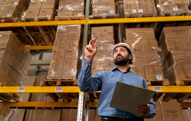 Foto mann mit helm, der im lager arbeitet