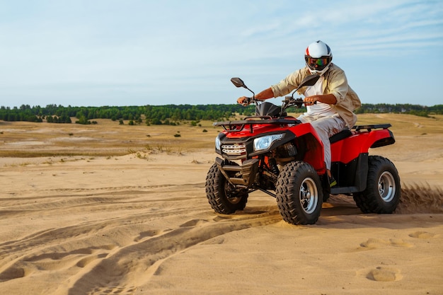 Mann mit Helm fährt auf einem ATV im Wüstensand