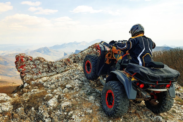 Mann mit helm sitzt auf einem quad in den bergen