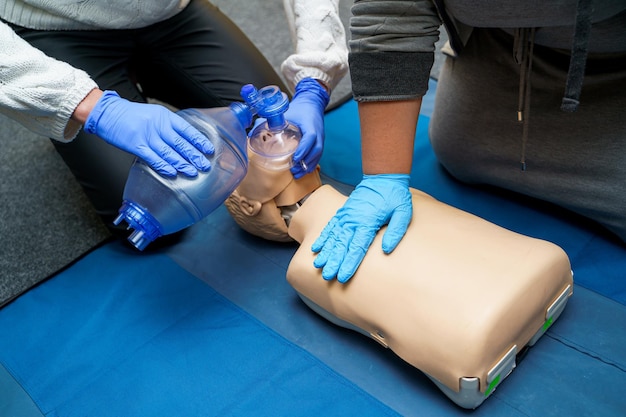 Mann mit HLW-Technik am Dummy im Erste-Hilfe-Kurs Sauerstoffmaske auf medizinischer Puppe Stock-Foto