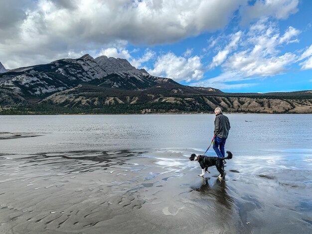 Foto mann mit hund in den bergen gegen den himmel in jasper alberta in voller länge