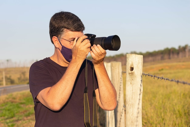 Mann mit Kamera beim Fotografieren im Feld