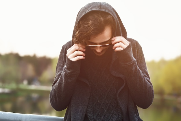 Mann mit Kapuze steht auf der Brücke und der Mann trägt eine Sonnenbrille