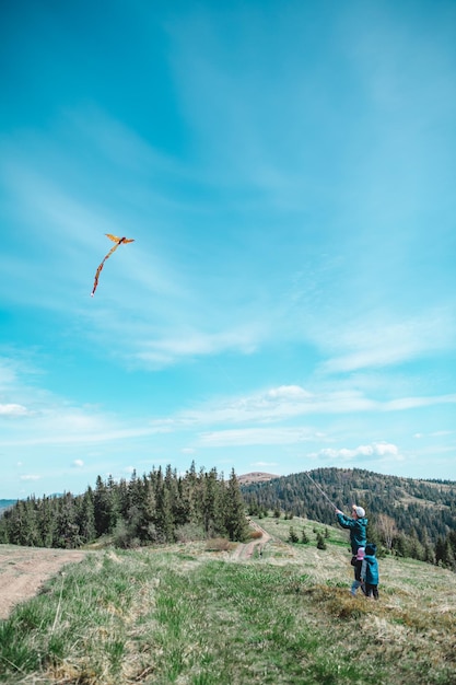 Mann mit Kindern, die draußen mit Drachen spielen, der Wind fängt und Spaß hat