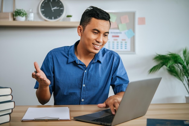 Mann mit Kopfhörern arbeitet im Büro mit Papieren und Laptop auf dem Schreibtisch