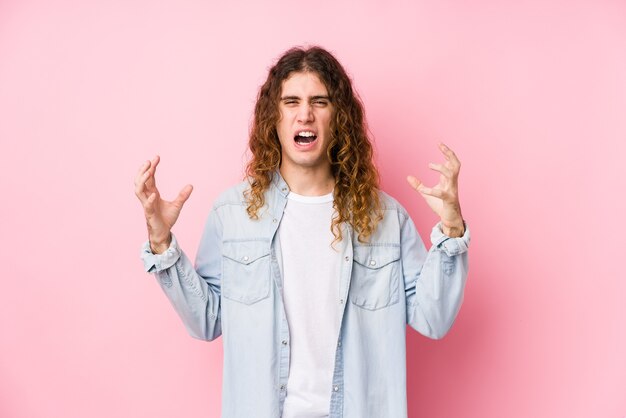 Mann mit langen Haaren, der isoliert vor Wut schreit.