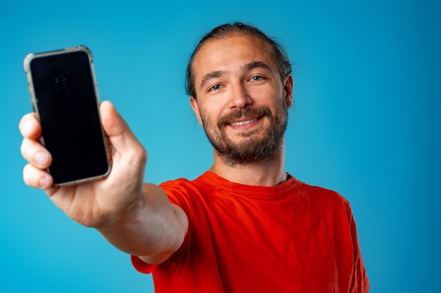 Mann mit langen Haaren hält Telefon