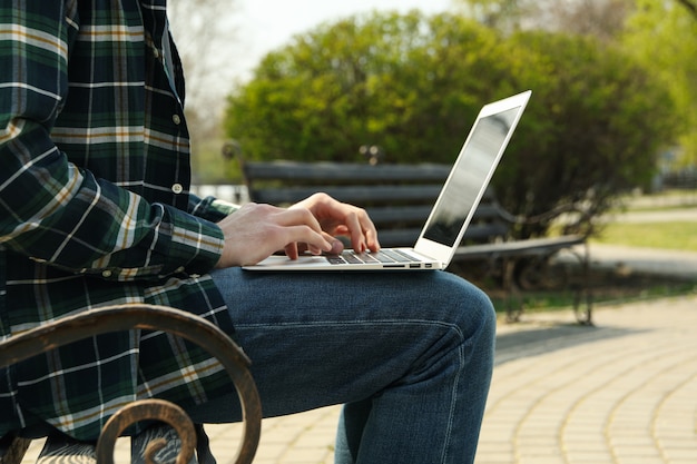 Mann mit Laptop arbeitet im Park. Arbeiten im Freien