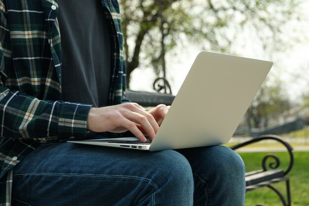 Mann mit Laptop arbeitet im Park. Arbeiten im Freien