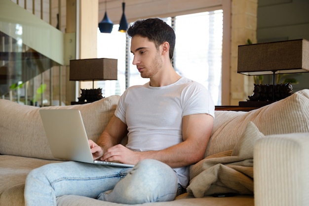 Mann mit Laptop im Wohnzimmer