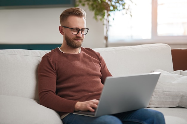 Mann mit Laptop im Wohnzimmer