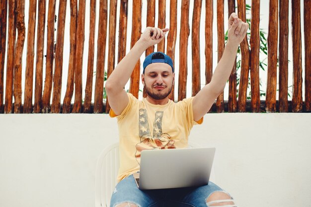 Mann mit Laptop tanzen beim Musikhören gegen einen Holzzaun