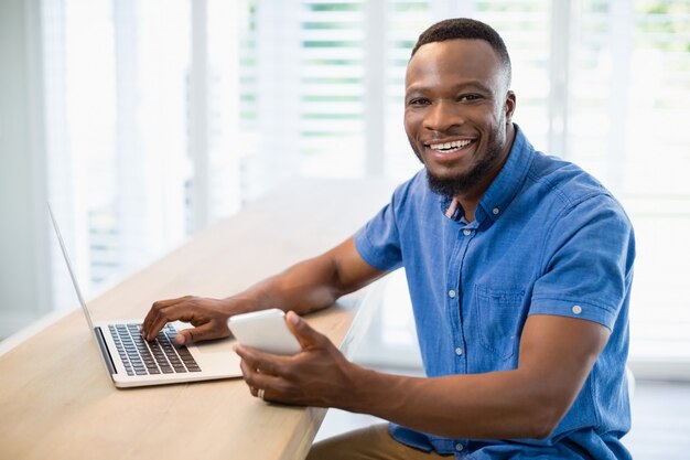 Mann mit Laptop und Handy im Wohnzimmer zu Hause