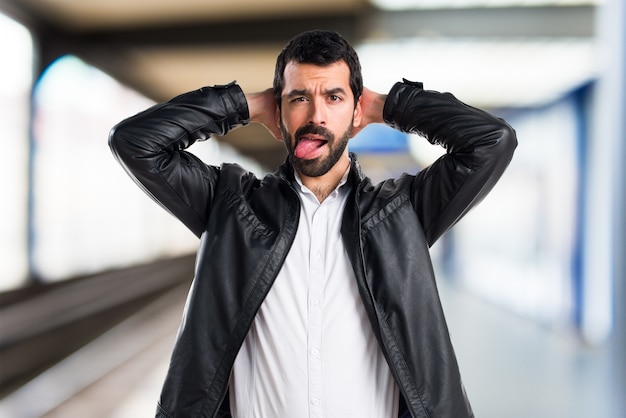 Mann mit Lederjacke, die seine Zunge auf unfocused Hintergrund herauszieht