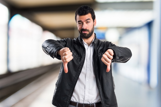 Mann mit Lederjacke tut schlechtes Signal auf unfocused Hintergrund