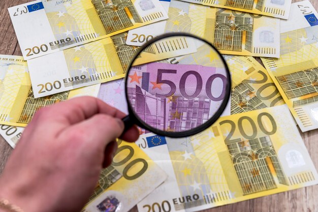 Mann mit Lupe findet Euro-Banknoten
