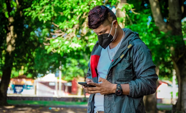 Mann mit Maske SMS mit seinem Handy junger Mann mit Maske SMS mit seinem Handy