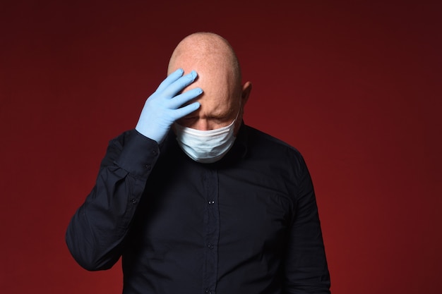 Mann mit Maske und Latexhandschuhen auf dem Kopf auf rotem Hintergrund