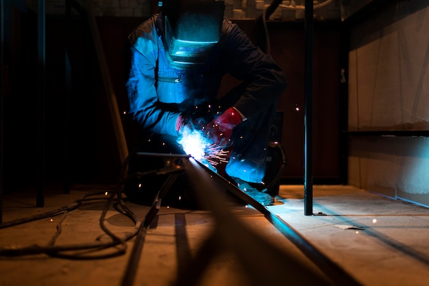 Mann mit Maskenschweißen von Metall im Atelier