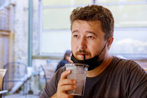 Mann mit Maskentrinkwasser im Restaurant