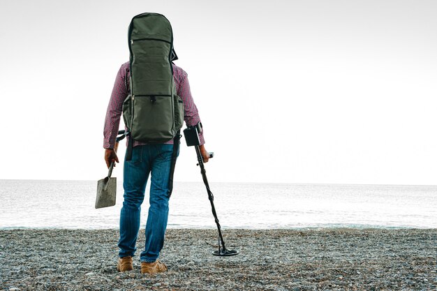 Mann mit Metalldetektor auf der Suche nach verlorenen Schätzen am Strand