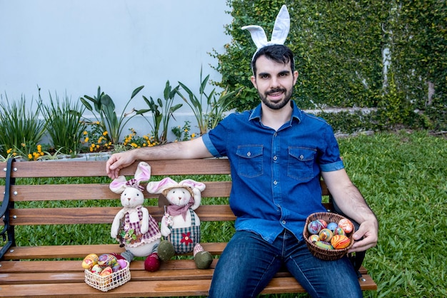 Mann mit Osterhasenohren auf Parkbank