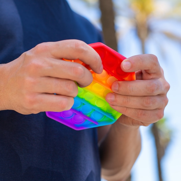 Mann mit Regenbogen-Anti-Stress-Spielzeug im Freien