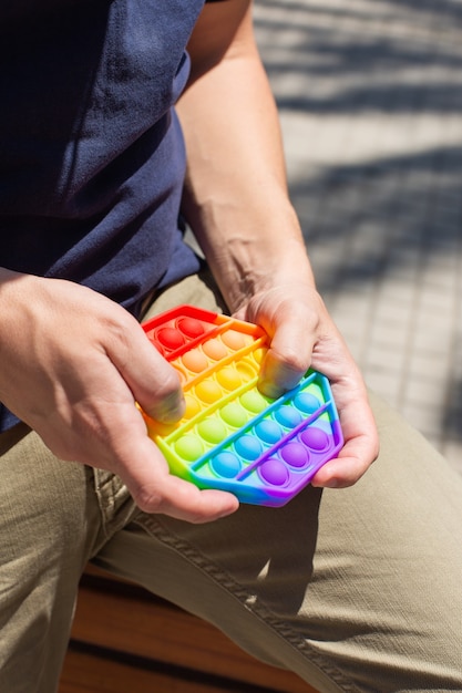 Mann mit Regenbogen-Anti-Stress-Spielzeug im Freien