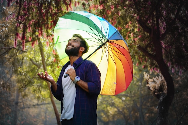 Mann mit Regenschirm im Frühjahr mit Blumen im Hintergrund