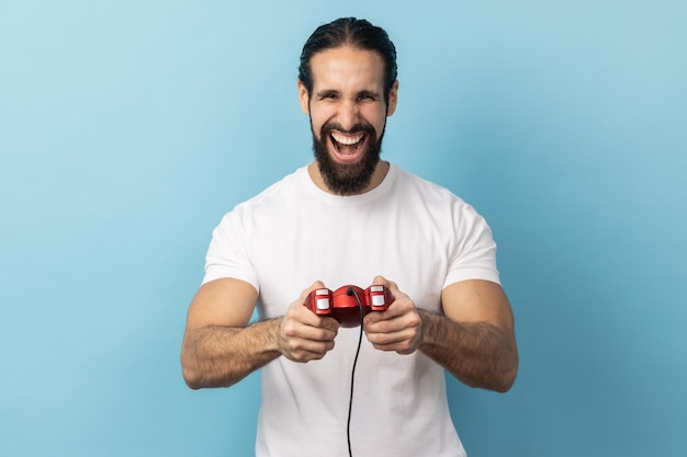 Mann mit rotem Gamepad-Joystick, der mit optimistischem Ausdruck in die Kamera blickt und das Spiel genießt