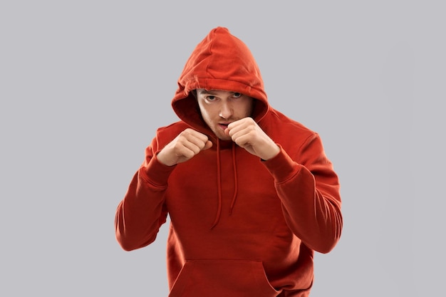 Mann mit roter Kapuze kämpft mit Fäusten oder Boxen