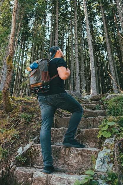 Mann mit Rucksack, der über eine Steintreppe geht, die zum Wald führt