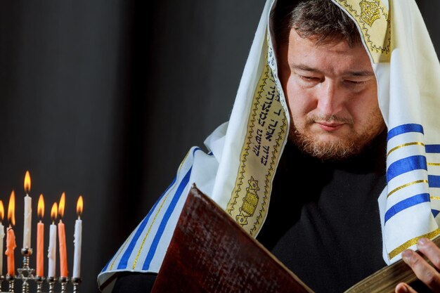 Foto mann mit schal liest ein buch bei farbenfrohen brennenden kerzen