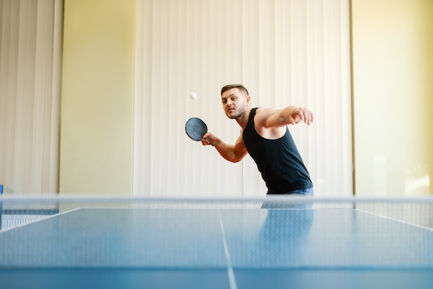 Mann mit Schläger und Ball spielen Tischtennis drinnen