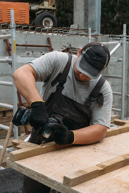 Mann mit Schraubendreher bei der Arbeit mit Holzmaterialien auf der Baustelle