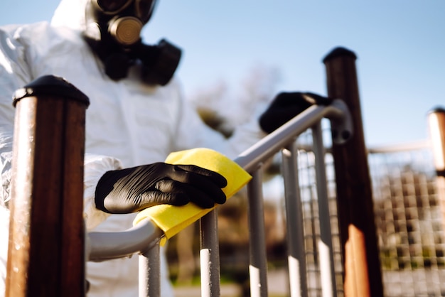 Mann mit Schutzanzug wäscht und desinfiziert den Spielplatz, um die Ausbreitung der Epidemie zu verhindern.