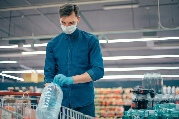 Mann mit Schutzmaske kauft Wasser in einem Supermarkt. Foto mit Textfreiraum