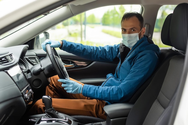 Mann mit Schutzmaske und Handschuhen beim Autofahren. Infektionsprävention und Epidemiebekämpfung. Weltpandemie. Pass auf dich auf.