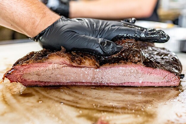 Foto mann mit schwarzen handschuhen drückt saftige geräucherte grillbrustfleisch