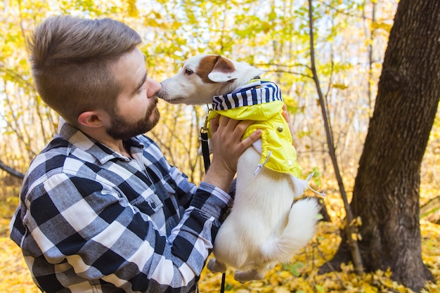 Foto mann mit seinem hund im herbstpark. kerl spielt mit jack russell terrier im freien. haustier und leute