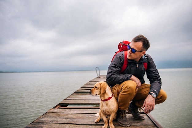 Mann mit seinem Hund sitzt am Dock