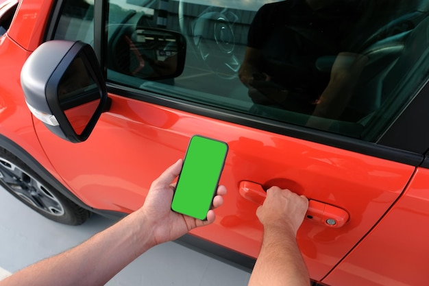 Mann mit Smartphone in der Hand neben dem Auto halten