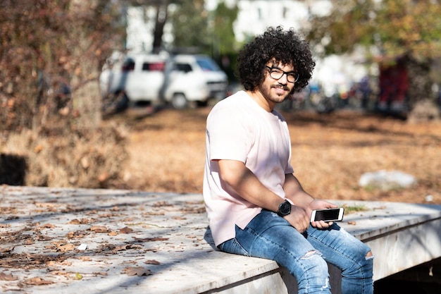 Mann mit Smartphone in einem Herbstpark