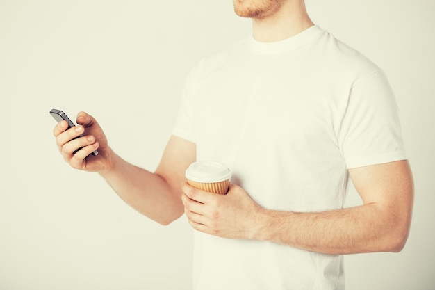 Mann mit Smartphone und Kaffeetasse zum Mitnehmen