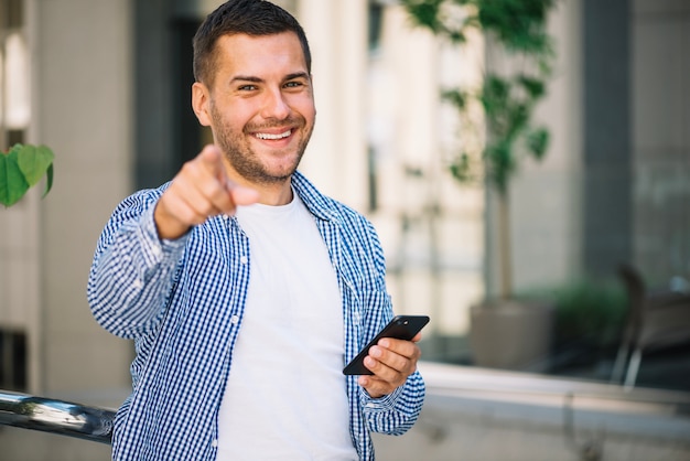 Foto mann mit smartphone zeigend auf sie