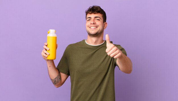 Mann mit Smoothy, der sich stolz, sorglos, selbstbewusst und glücklich fühlt und positiv mit Daumen nach oben lächelt