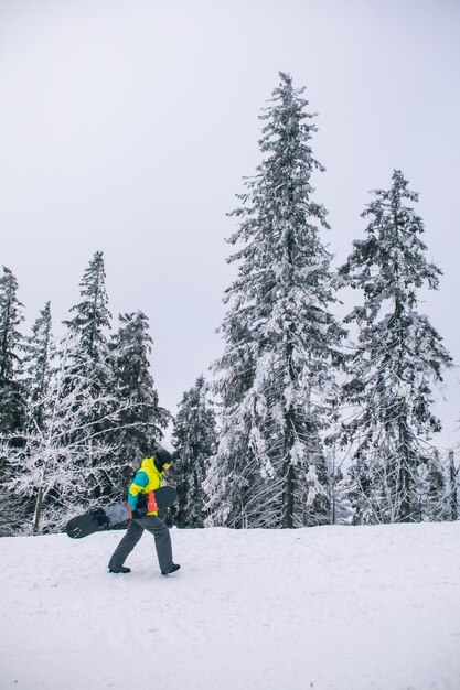 Mann mit Snowboard zu Fuß durch verschneite Hügel Winteraktivitäten