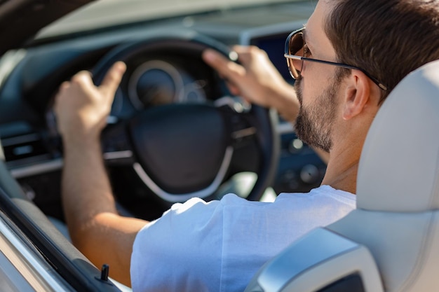 Mann mit Sonnenbrille, der Cabrio-Rückansicht fährt