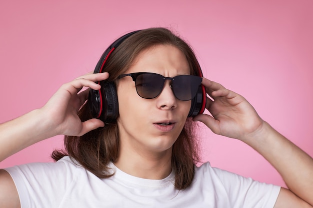 Mann mit sonnenbrille hört musik mit kopfhörern und tanzt