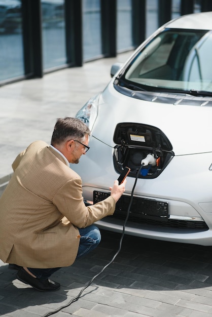 Mann mit Stromanschluss für Elektroauto